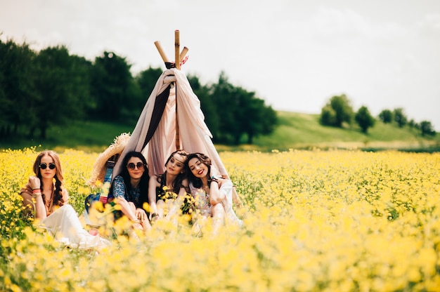 four beautiful hippie girl in a field of yellow flowers