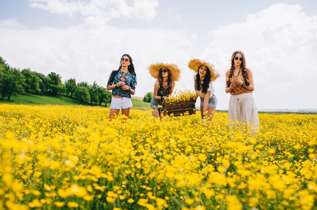 Photo four beautiful hippie girl in a field of yellow flowers