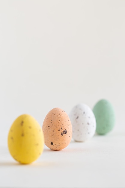 Four beautiful pastel colored chocolate Easter eggs one pink egg sharp on white background with copy