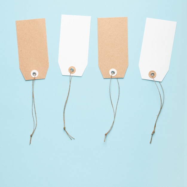 Four blank paper price tag with a knotted string on a blue background