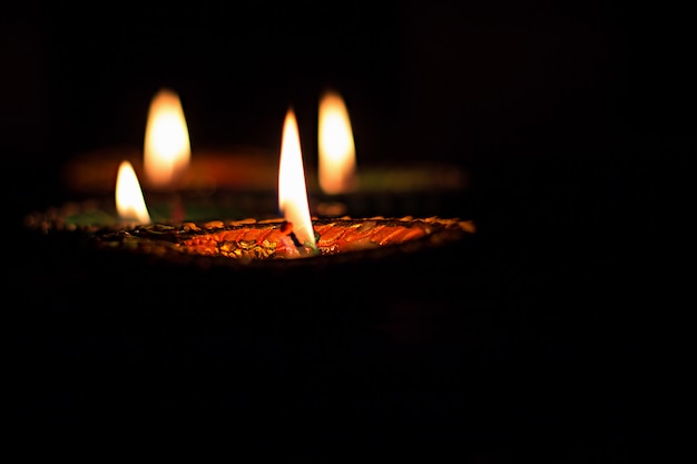黒の背景にディワリ祭のお祝いのための4つの燃焼カラフルなキャンドルインド風。