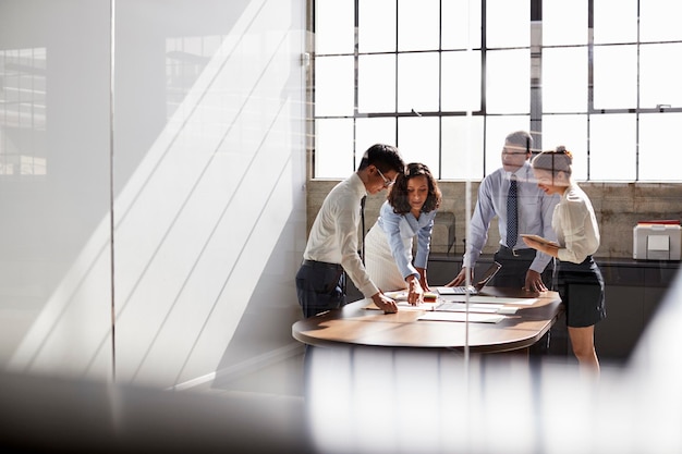 Photo four business colleagues stand talking in a meeting room