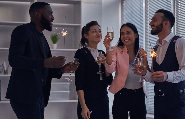 The four business people drinking champagne and holding sparklers