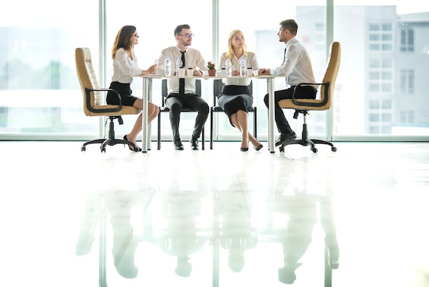 The four business people sit at the table and discuss