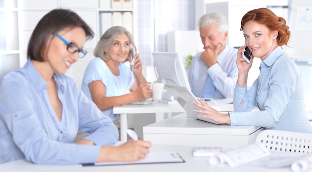 Four Businesspeople Working At Desks In Office