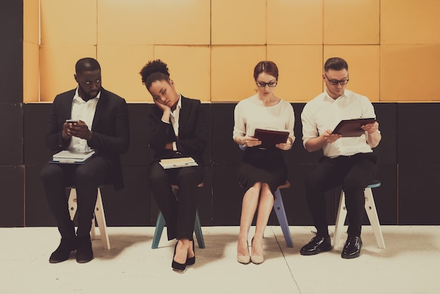 Four Busy Managers Sitting On Chairs In Office.