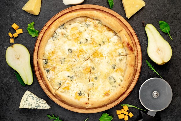 Pizza ai quattro formaggi con ingredienti su fondo in pietra