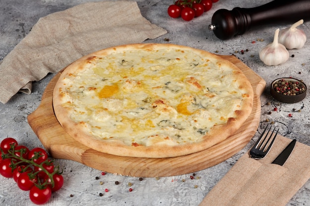 Four cheese pizza on wooden board, gray background