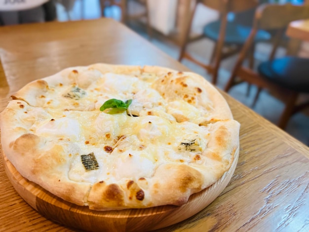 four cheeses pizza on the table in the pizzeria creamy base mozzarella ricotta dor blue and basil selective focus