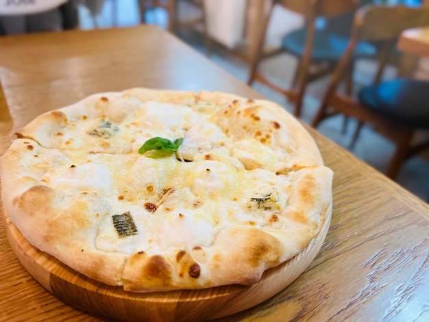 Four cheeses pizza on the table in the pizzeria Creamy base mozzarella ricotta dor blue and basil selective focus