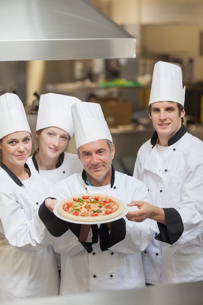 Фото Четыре шеф-повара держат пиццу
