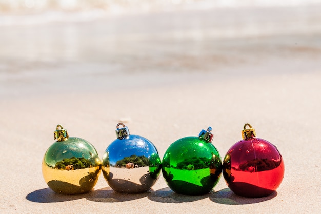 Four christmas decoration balls on sea beach sand