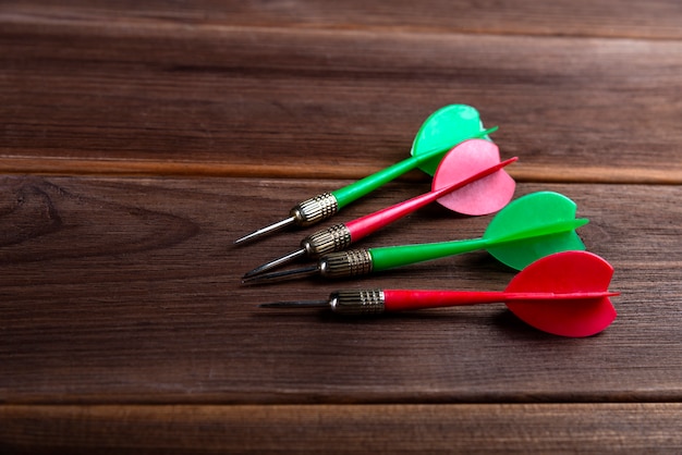 Four colored darts on a wooden background. Hit the target