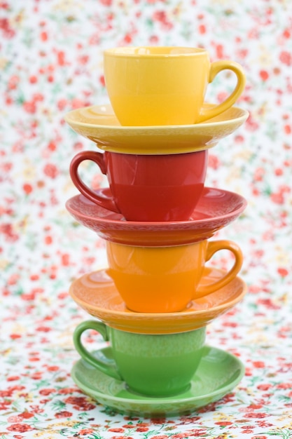 Four colorful cups and balls of yarn on a background of a red flower