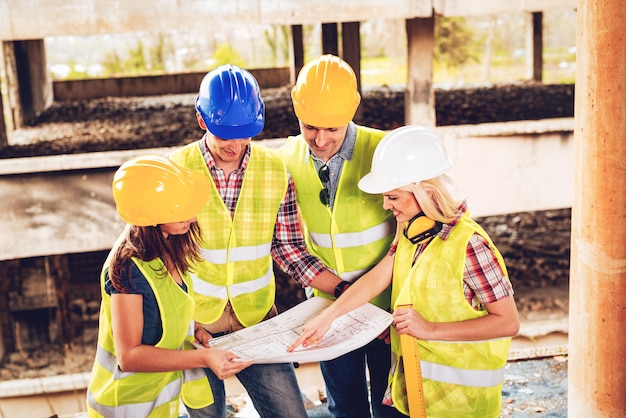 Four construction architects in the building damaged in the disaster. Smiling looking at plan.