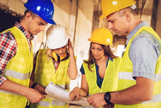 Photo four construction architects review plan of building damaged in the disaster.