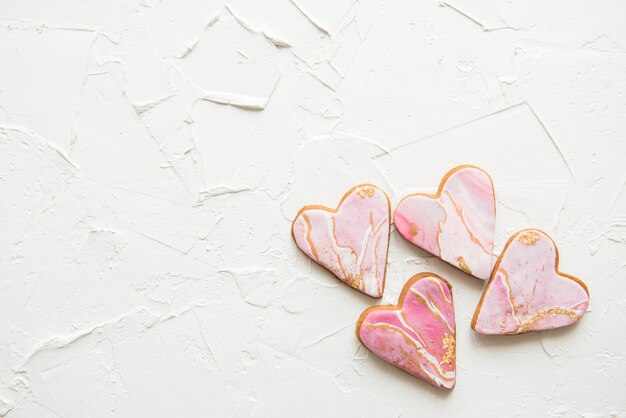 Four cookies in the shape of marble white hearts on wooden wall