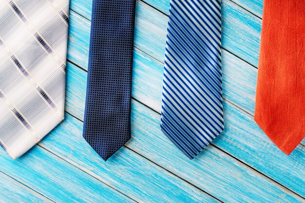 Four different colored ties in row on wooden blue background