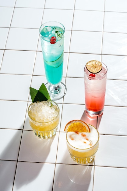 Four different refreshing cocktails on a white tile table