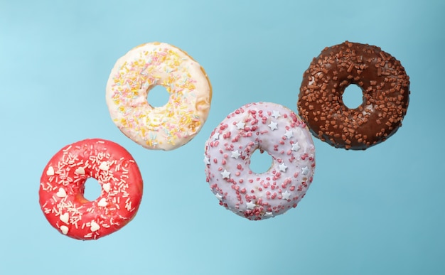 Four different tasty donuts on blue background