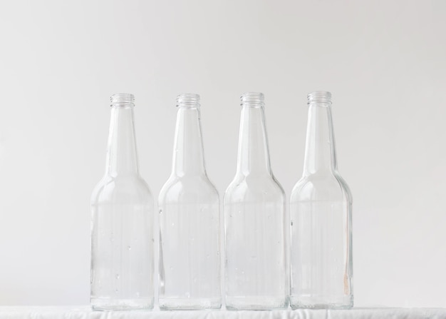 Foto quattro bottiglie vuote su uno sfondo bianco il concetto di estetica dei contenitori di vetro delle bottiglie