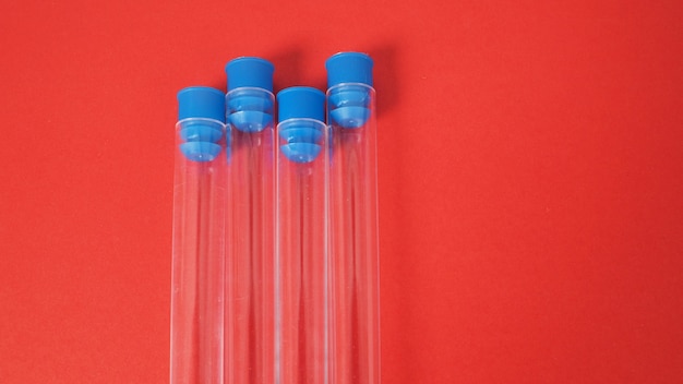 Four empty test tubes on red background.