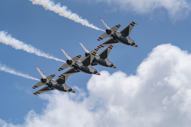 Four fighter jets fly in formation with smoke coming out of them.