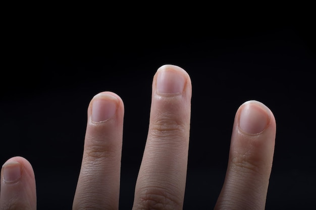 Four fingers of a child hand partly seen in black background