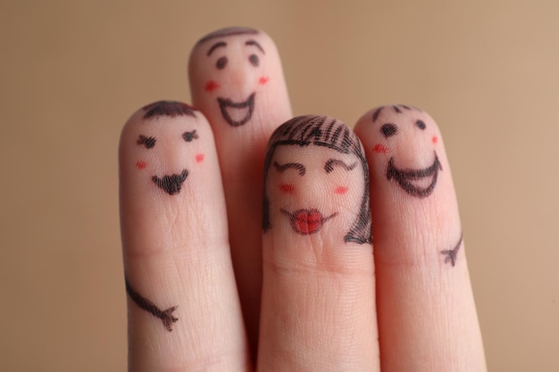 Four fingers with drawings of happy faces on brown background