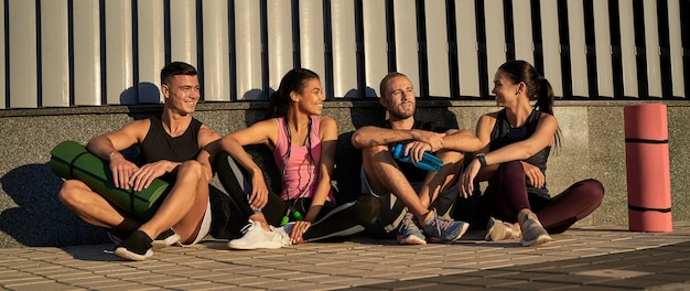 Four friends athletes sitting and communicating with each other