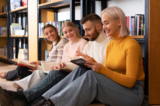 Four friends reading books in a library during study session
