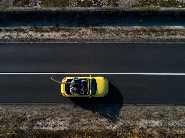 The four friends traveling by yellow cabriolet