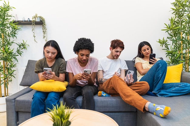 Four friends of various ethnicities are absorbed in their mobile phones sitting together