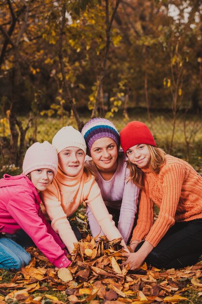 Four girls playing with autumn leaves and smiling