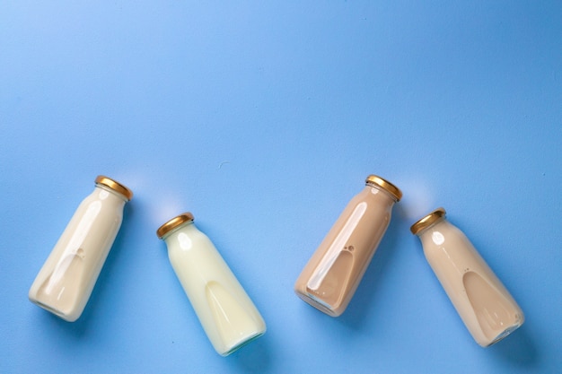 Photo four glass bottles of flavoured milk on blue flatlay