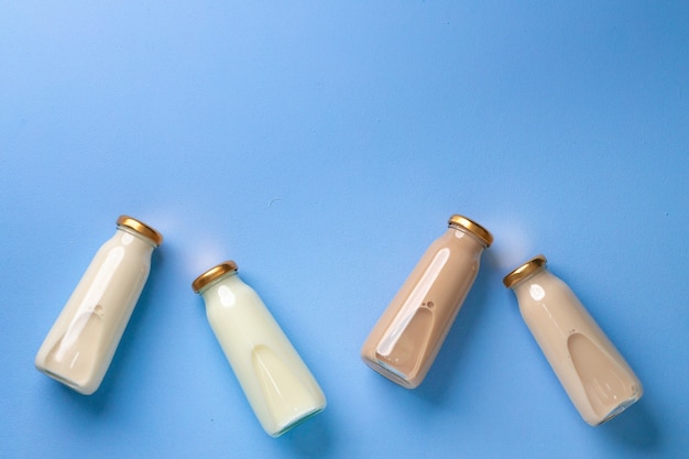 Four glass bottles of flavoured milk on blue flatlay