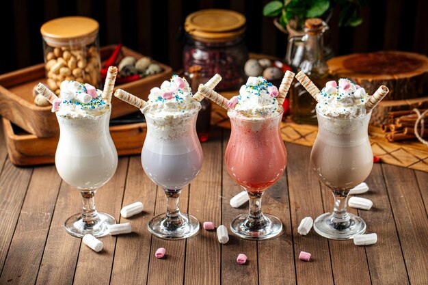 Four glasses of sweet milkshakes with biscuits