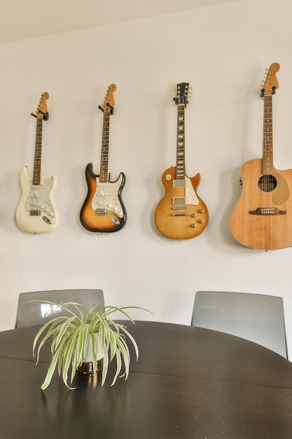 Photo four guitars hanging on the wall behind a table