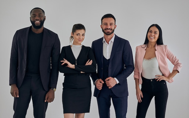 The four happy business people standing near wall