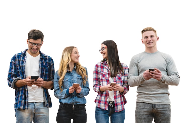 The four happy people with phones stand on the white wall background