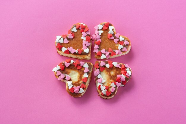 Four heart shaped pancakes decorated with little red and white hearts make a clover