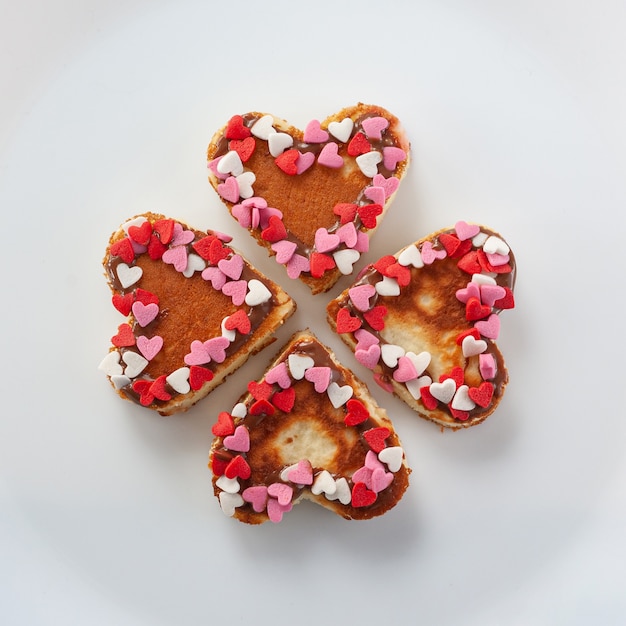 Four heart shaped pancakes decorated with little red and white hearts make a clover