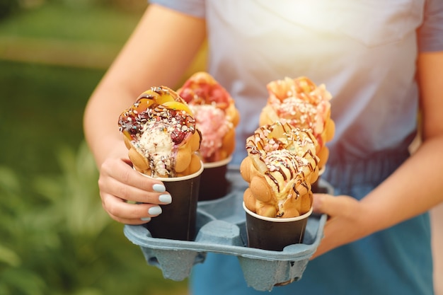 Four Hong Kong waffles in cups food delivery in hand of woman