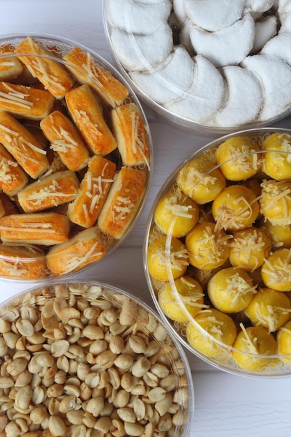 Four jars of Nastar Kaasstengels Vanillekipferl and Fried Peanuts on a table Half composition