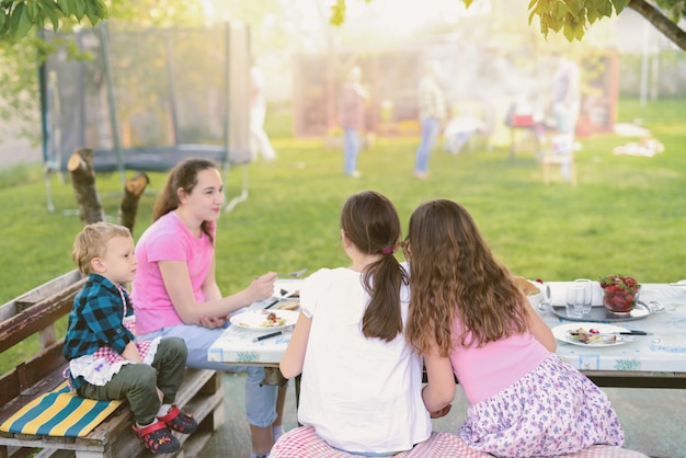 Four kids sitting by the table in nature and eating