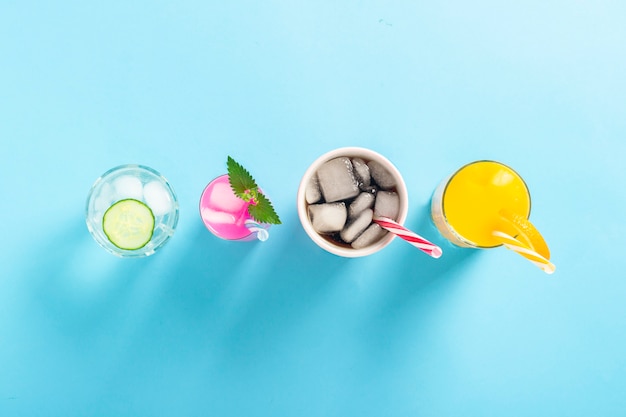 Photo four kinds of refreshing drinks with ice on a dark blue surface.  flat lay, top view