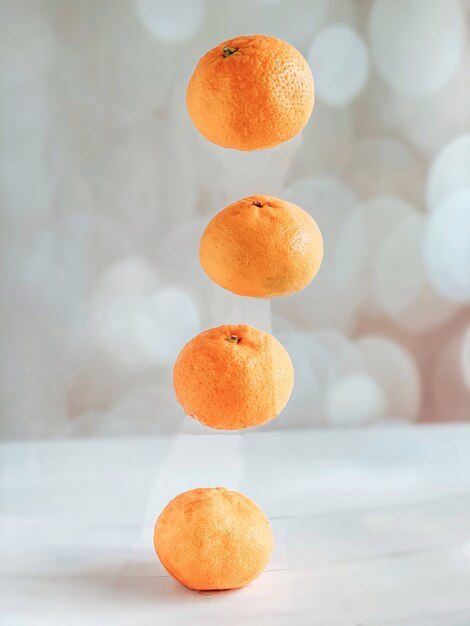 Four levitating tangerines on a beige background. The concept of a healthy lifestyle and nutrition, tangerines as a symbol of New Year's holidays.