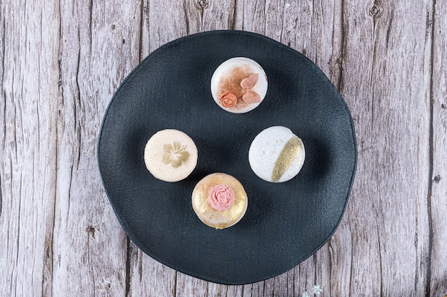 Four macarons decorated with edible ink and fondant on a black platetop view