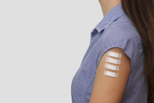 Four medical plasters on the arm of a young woman Symbol of four doses of covid-19 vaccinations.