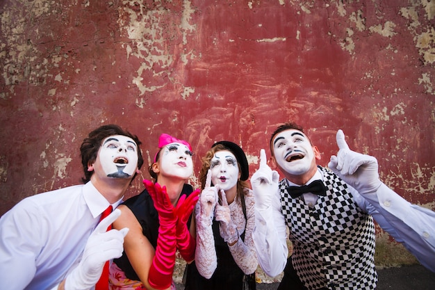 Four mimes point to the top on a red wall